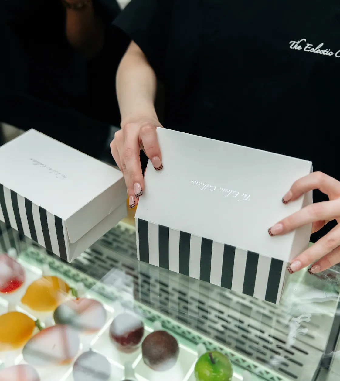A striped Eclectic Collection box being closed over a tray of bonbons