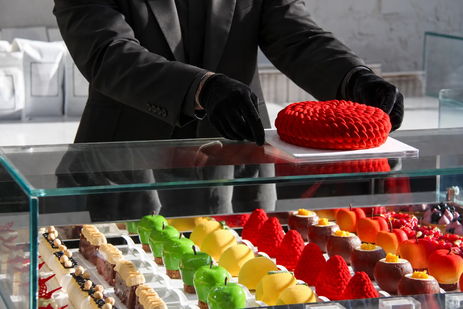 A whole cake being placed on the pâtisserie counter