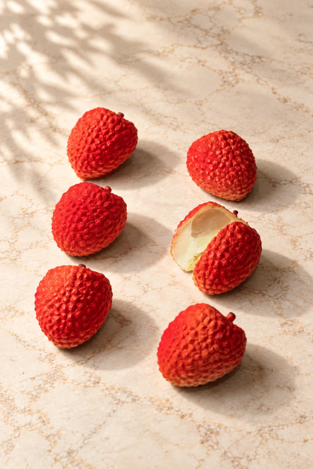Six Lychee pâtisserie on marble, one cut open