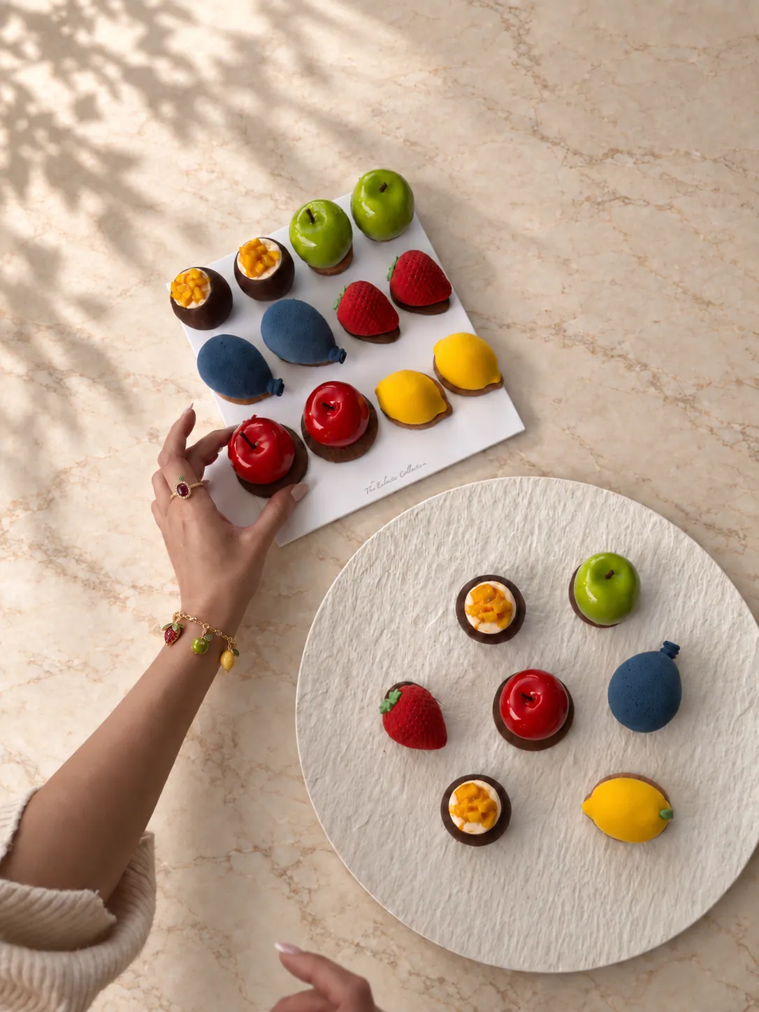 Miniature fruit shaped pâtisserie on a board and a plate