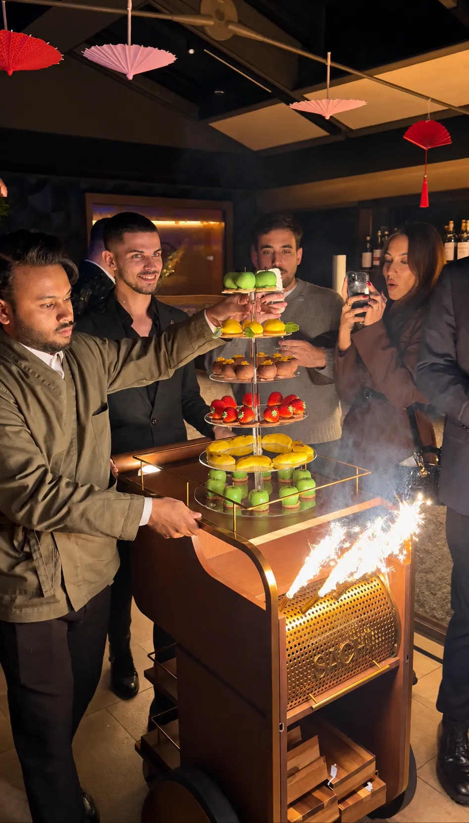 A tiered stand of miniature pâtisserie wheeled in with sparklers