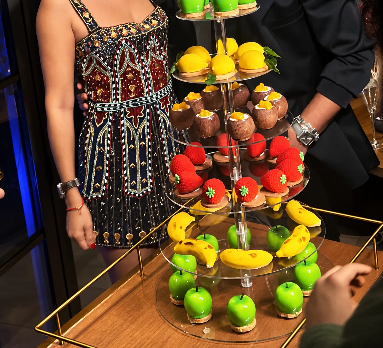 A tiered stand of miniature pâtisserie on a trolley at a party