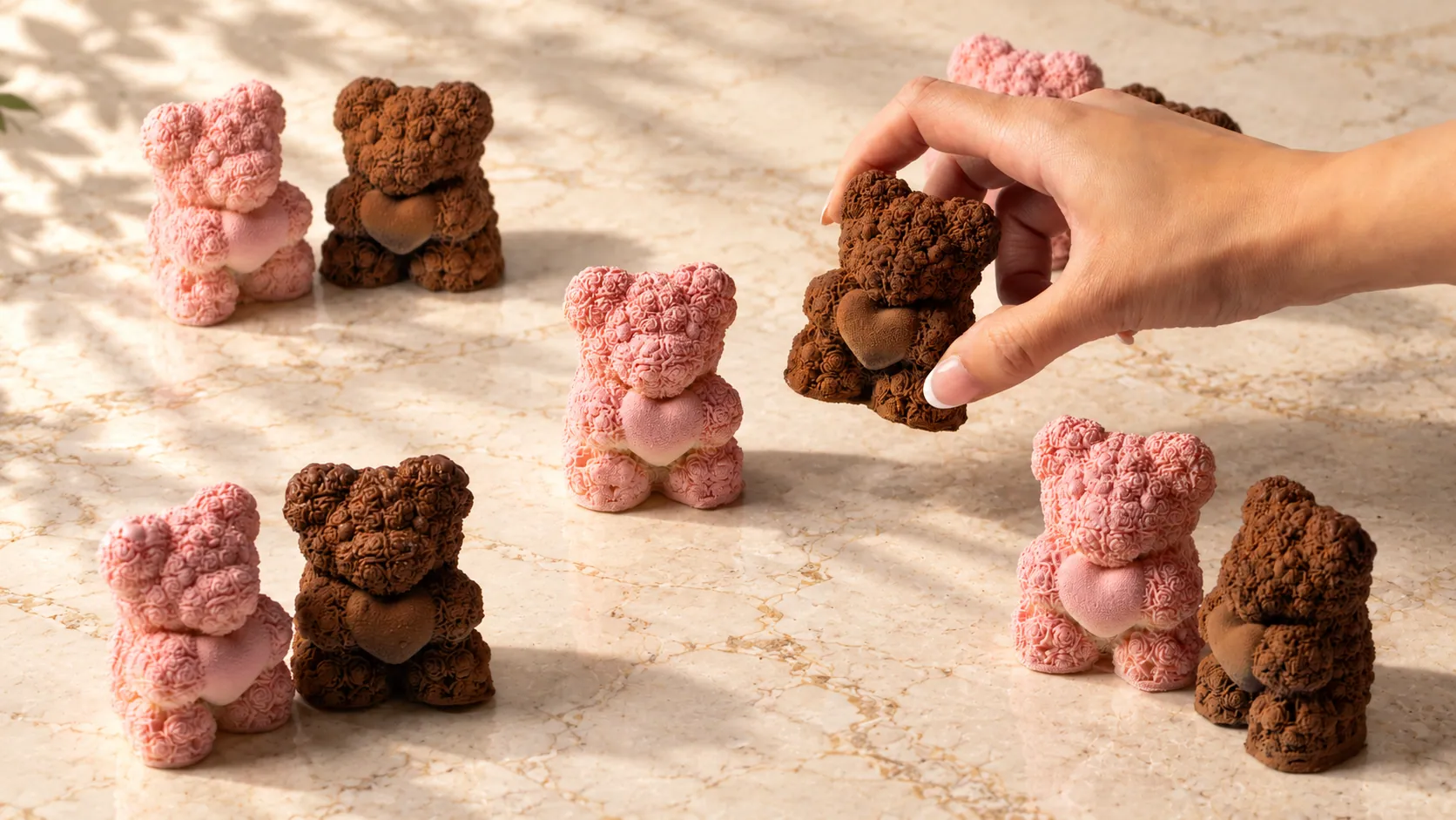 Bear shaped pâtisserie in pink and chocolate, one being lifted by hand